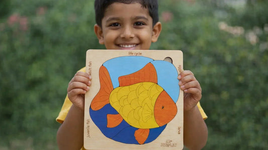 Smiling child holding a colorful wooden fish life cycle puzzle toy, promoting early learning, problem-solving skills, hand-eye coordination, and cognitive development through educational play.